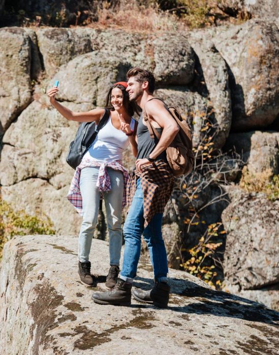 Young happy couple taking selfie in mountains with smartphone